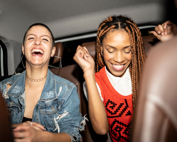 Twee jongeren lachend en feestend op de achterbank van een auto